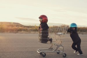 Young businessmen and boys dressed in business suits and racing helmets are ready to race their business to new levels. Boys race in a shopping cart in a Utah valley.